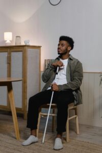 Photo, a man sitting in an office with a white vision & mobility cane